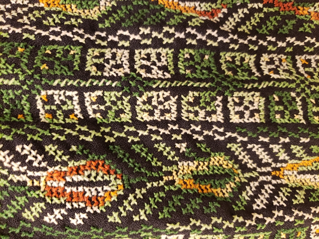 Green, yellow, and white Palestinian cross-stitch on black cotton